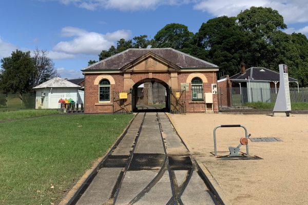 Brick building in the background with railway tracks leading into it in the foreground.